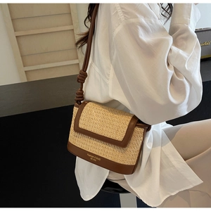 Detail of woven straw crossbody bag with contrast leather trim and knot strap design