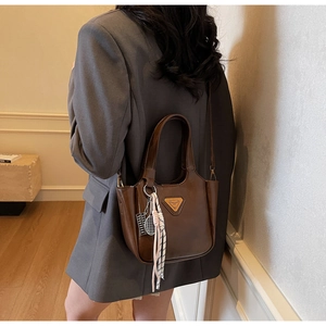 Détail d'un cabas en cuir marron avec plaque métallique et ruban rayé élégant