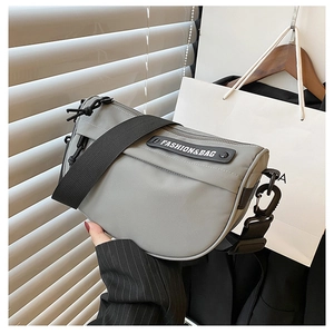 Macro shot of neutral grey nylon saddle bag with fashion brand label and wide strap