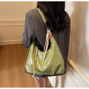 Détail du sac hobo vert avec sangle tissée colorée porté par un mannequin