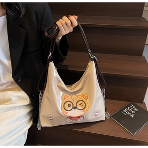 Detail of cream patent leather tote featuring cute cartoon bear patch and chain strap