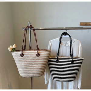 Large woven beach tote bag with striped pattern and leather straps in a casual setting
