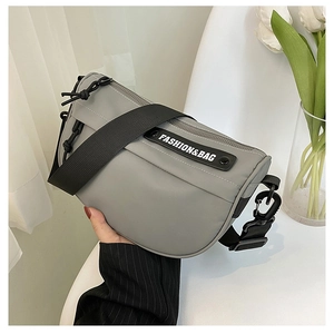 Close-up of a grey nylon saddle bag with wide adjustable strap and fashion lettering