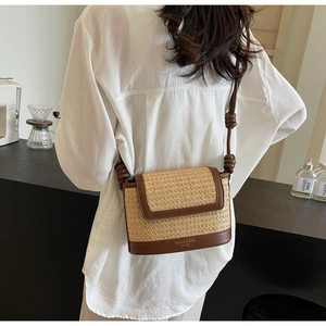 Detail of woven straw crossbody bag with brown leather trim and knotted shoulder strap