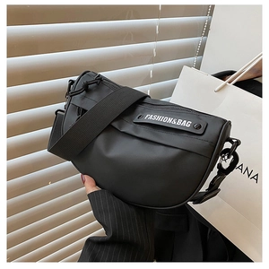 Detail of black nylon saddle bag featuring wide strap and fashion brand label detail