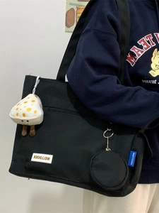 Black canvas tote bag with mushroom charm and mini wallet shown on model shoulder
