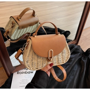 Detailed close-up of woven straw handbag texture with brown leather flap and metal buckle