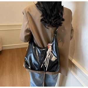 Détail d'un grand cabas en cuir verni noir brillant avec breloque à pompon coloré