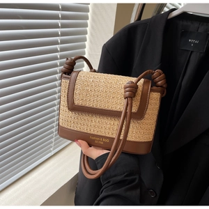 Close-up of woven straw crossbody bag featuring brown leather trim and knotted strap