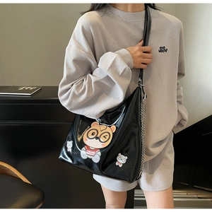 Detail of black glossy tote bag featuring a cute cartoon bear patch and panda accents