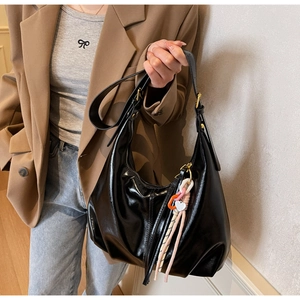 Détail du sac hobo noir brillant avec pendentif cœur et bandoulière réglable