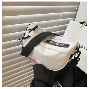 Detail of white nylon saddle bag featuring a wide strap and fashion brand logo plate
