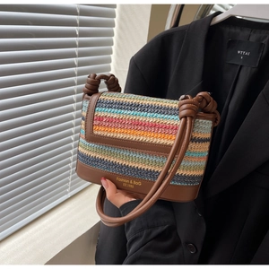Detail of colorful striped straw bag featuring leather knotted handle and logo printed base