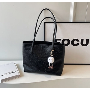 Detail of black embossed tote bag featuring HOT and LIFE lettering with a plush charm