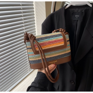 Detail of colorful woven straw crossbody bag with brown leather trim and knotted strap