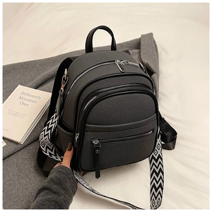Close-up of gray canvas backpack featuring black leather trim and woven geometric shoulder strap