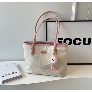 Detail of embossed floral patterns on cream tote bag with pink straps and plush charm