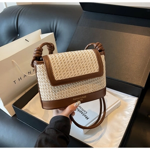 Detailed shot of beige woven bag with brown leather trim and knot shoulder strap detail