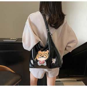 Detail of glossy black tote bag featuring cute cartoon bears and silver chain strap accent