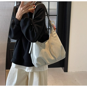 Détail d'un sac hobo gris avec plis latéraux et large bandoulière porté par un mannequin