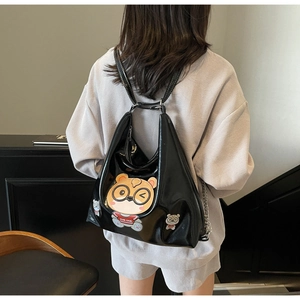 Close-up of glossy black tote bag featuring a cute cartoon bear and metallic finish