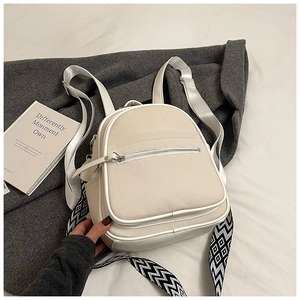 Detail of cream canvas backpack with geometric patterned straps on minimalist bedding