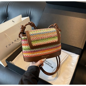 Detail of colorful woven crossbody bag with brown leather trim and fashion logo branding