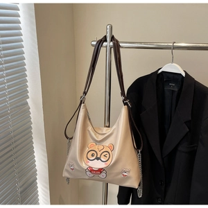Detail view of beige tote bag with bear print and stylish silver chain decoration