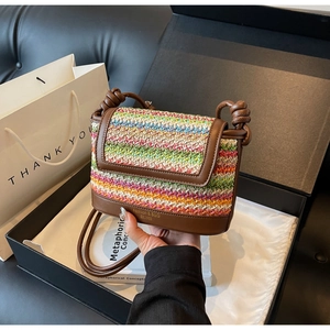 Detail of handmade rainbow straw bag with brown leather trim and stylish woven knots