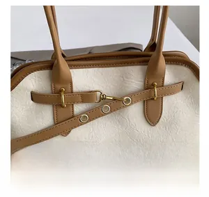 Detail view of the textured beige tote bag with brown leather accents and gold hardware