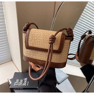 Detail of woven straw crossbody bag with brown leather trim and knotted strap design