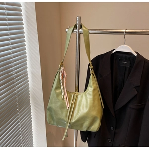 Détail du sac hobo vert olive avec pompon tressé et texture plissée élégante