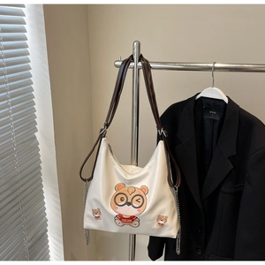 Close-up of cream tote bag featuring a cute cartoon bear print and brown shoulder straps