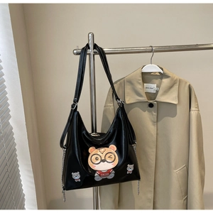 Detail of glossy black tote bag with cartoon bear print and silver decorative chain
