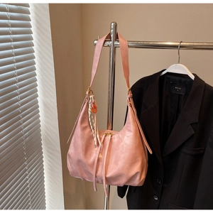 Détail du sac hobo rose avec bandoulière réglable, pompon décoratif et cuir souple