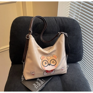 Detail of beige tote bag featuring a cute cartoon bear print and stylish metal chain strap