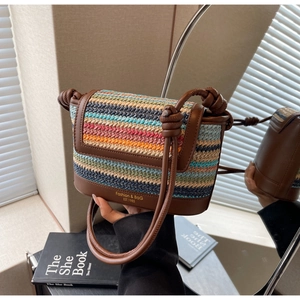 Macro detail of multicolored straw weave bag with leather flap and gold lettering