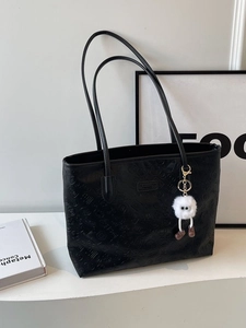 Black embossed faux leather tote bag with monster charm and spacious interior for work