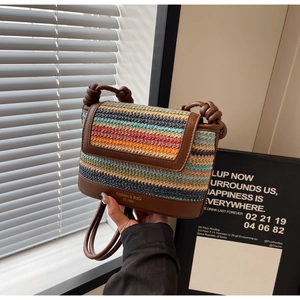 Close-up of colorful striped straw crossbody bag with brown leather trim and gold lettering