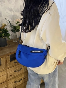 Blue nylon crescent saddle bag with wide adjustable strap and fashion label detail