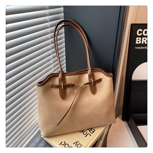 Detail of beige and brown leather tote bag showing textured grain and metal buckle