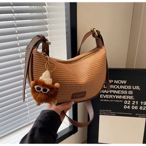 Brown woven half-moon crossbody bag with leather patch and cute plush monster charm