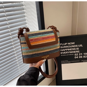 Detail showing contrast color woven straw texture and leather flap with gold lettering