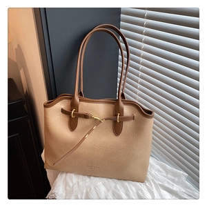 Detail of minimalist tote bag showing beige wrinkled leather and dark brown handles
