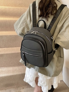 Charcoal grey minimalist backpack with adjustable straps worn by a female model