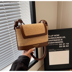 Close-up of woven straw handbag with brown leather trim and stylish knotted handle