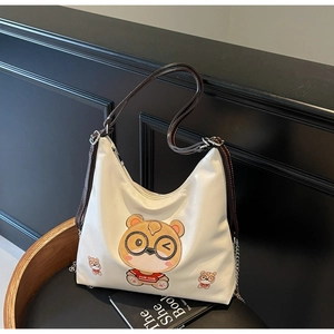 Detail of white tote bag featuring cartoon bear print and decorative silver chains