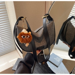 Detail of textured woven shoulder bag with leather straps and plush charm accessory