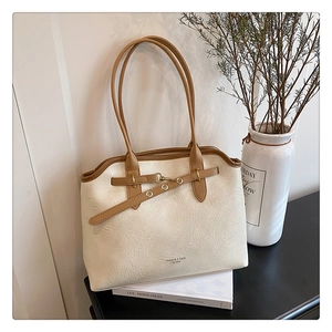 Detail view of cream tote bag with brown straps and textured leather finish