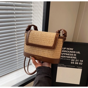 Detail of hand-woven straw crossbody bag featuring brown leather trim and knot handle